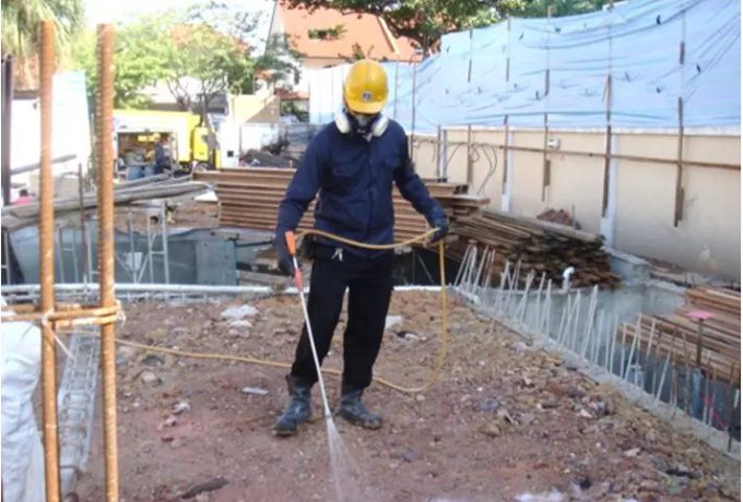 Kỹ thuật viên phun thuốc tồn lưu xuống đất nền công trình trước khi đổ bê tông
